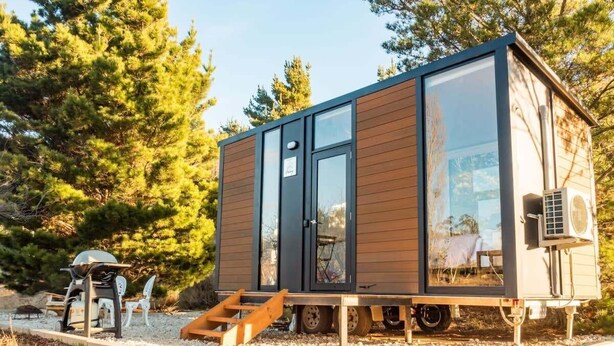 A small cabin with a sliding door, a window, and a small porch area. - Blue Gum at Langdale 1 by Tiny Away (Bungendore)
