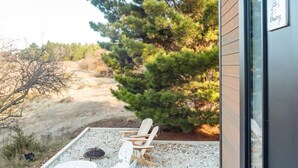 A modern building with a patio area featuring a wooden chair and a small table. - Blue Gum at Langdale 1 by Tiny Away (Bungendore)