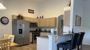 Een moderne keuken met een vast eiland, roestvrijstalen apparatuur en houten vloeren.