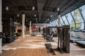 Ett gym med träningsutrustning, löpband och stora fönster.