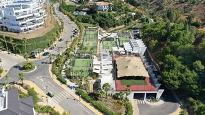 An aerial view of a residential area with modern buildings, a road, and green spaces.
