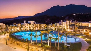 Ein Resort mit großem Pool, umgeben von Palmen und einem Bergpanorama.