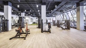 A gym with various exercise equipment, large windows, and a high ceiling. - Mirador Hills 2 | Estepona Luxury Apartment Pools (Estepona)