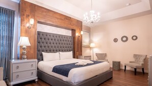 Une chambre d’hôtel moderne avec un grand lit, des panneaux de bois, un lustre et une petite table d’appoint.