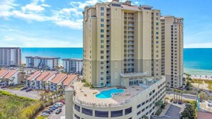 A high-rise hotel with a rooftop pool, multiple balconies, and a view of the beach and ocean. - Steps to the beach! 2 king beds, ice maker, see the Gulf and unwind in comfort! (Panama City Beach)