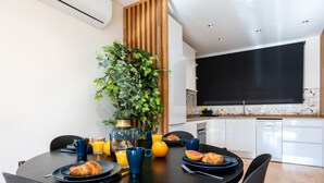 A modern dining area with a round table, chairs, breakfast items, and a potted plant. - Cosy apartment near the centre (Torremolinos)