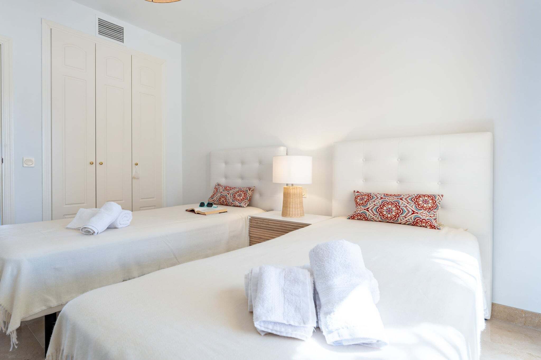 Ein Hotelzimmer mit zwei Betten, einem Kleiderschrank und einem Nachttisch mit Lampe.