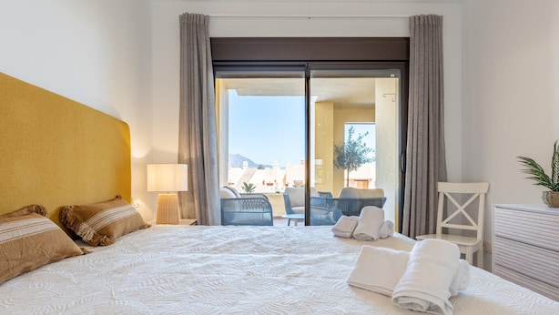 A hotel room with a large bed, a view of the outdoor seating area, and a sliding door leading to the balcony. - Cosy apartment in Manilva with shared pool (Manilva)