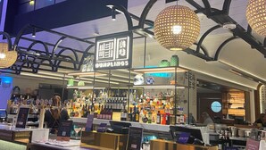A modern bar area with a sign for dumplings, a variety of liquor bottles, and a counter with a menu.
