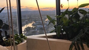A room with a large window overlooking a cityscape at sunset.