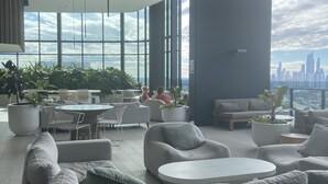 A modern lounge with a large sofa, round tables, and potted plants.