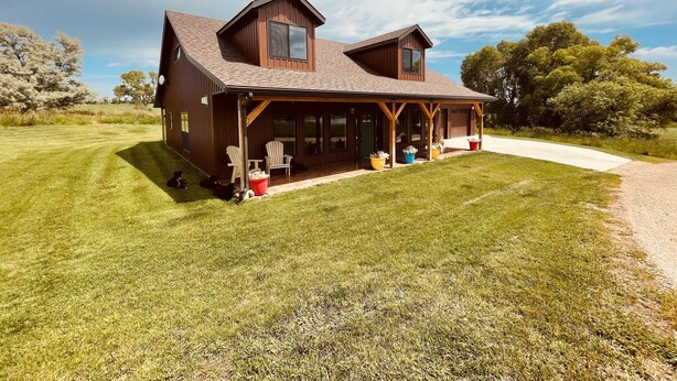 A two-story wooden house with a covered porch, large windows, and a well-maintained lawn. - 3 bedroom guest house with mountain views in Big Horn, Wyoming (Sheridan)