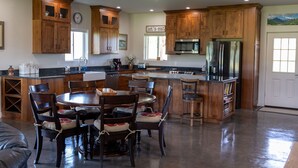 A spacious kitchen with wooden cabinets, a central island, and a dining area with chairs. - 3 bedroom guest house with mountain views in Big Horn, Wyoming (Sheridan)