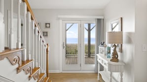 Eine Treppe mit weißen Balustraden und Holzhandläufen, die zu einer Tür mit Glasfeldern führt.