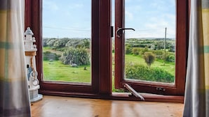 Habitació amb una finestra gran que ofereix vistes a un paisatge verd i un objecte decoratiu blanc al davant de la finestra.