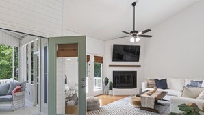 A spacious living room with a fireplace, a ceiling fan, and a large TV. - Kid Friendly! Upgraded Lake Front Cottage at Lake Martin! 35 Minutes to Auburn!  (Dadeville)
