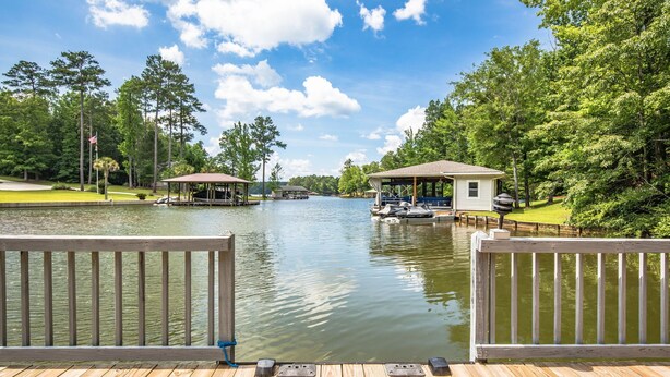 A wooden dock with a view of a calm lake, surrounded by trees and a small pavilion. - Kid Friendly! Upgraded Lake Front Cottage at Lake Martin! 35 Minutes to Auburn!  (Dadeville)