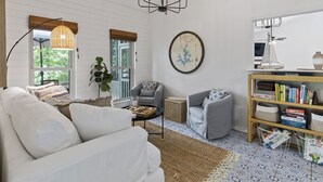 A cozy living room with a white sofa, two armchairs, a coffee table, and a bookshelf. - Kid Friendly! Upgraded Lake Front Cottage at Lake Martin! 35 Minutes to Auburn!  (Dadeville)