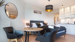 A modern bedroom with a bed, bedside tables, and a dining area with chairs and a table. - Apartment in Pobierowo near Beach and SPA (Pobierowo)