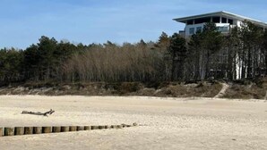 A modern beach house with a flat roof, large windows, and a view of the beach and forest. - Apartment in Pobierowo near Beach and SPA (Pobierowo)