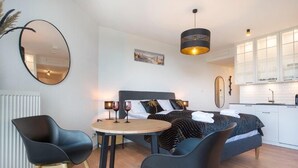 Ein modernes Schlafzimmer mit einem Bett, Nachttischen und einem Essbereich mit Stühlen.
