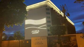 Ein Gebäude mit dem Schild "PINEA APARTMENTS" und einem Banner mit der Aufschrift "PINEA 2. ETAP JUŻ W SPRZEDZĄCY!".