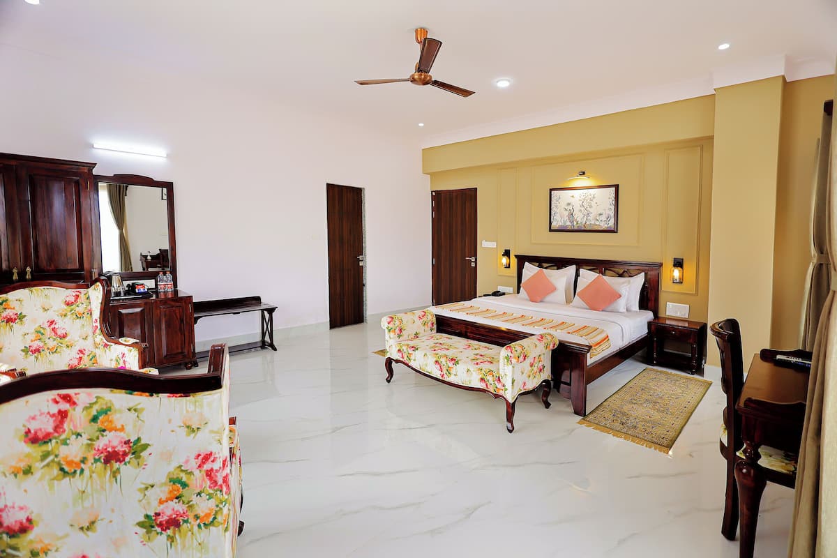 A hotel room with a bed, a desk, a chair, a wardrobe, and a ceiling fan.