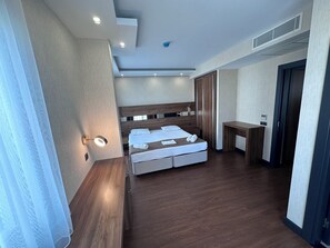 A modern hotel room with a wooden bed, a bedside table, a desk, and a wardrobe. - Star Suit Hotel (Trabzon)
