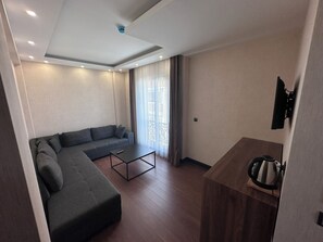 Suite Deluxe, 1 habitación, baño privado, vistas parciales al mar | Zona de estar | Una televisión, suelo radiante