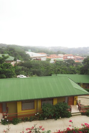 A building with a green roof, surrounded by greenery and other buildings in the background. - Hotel Ficus Monteverde (Monteverde)