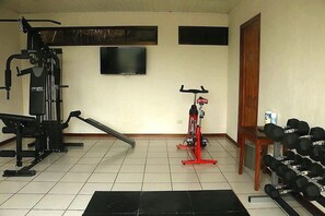 A gym with exercise equipment, a television, and a set of dumbbells. - Hotel Ficus Monteverde (Monteverde)