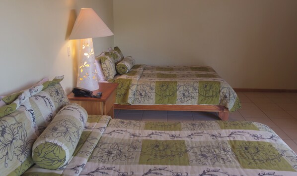 A bedroom with a bed, a bedside table with a lamp, and a chair. - Hotel Ficus Monteverde (Monteverde)
