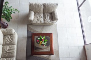 A room with a beige sofa, a wooden coffee table with a floral centerpiece, and a potted plant.
