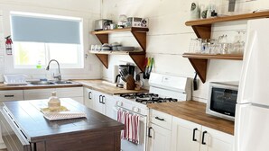 Een keuken met witte kasten, een houten eiland, een fornuis en een magnetron.