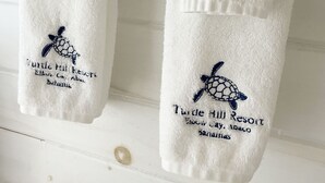 Twee witte handdoeken hangen aan een witte muur, met een klein decoratief object eronder.