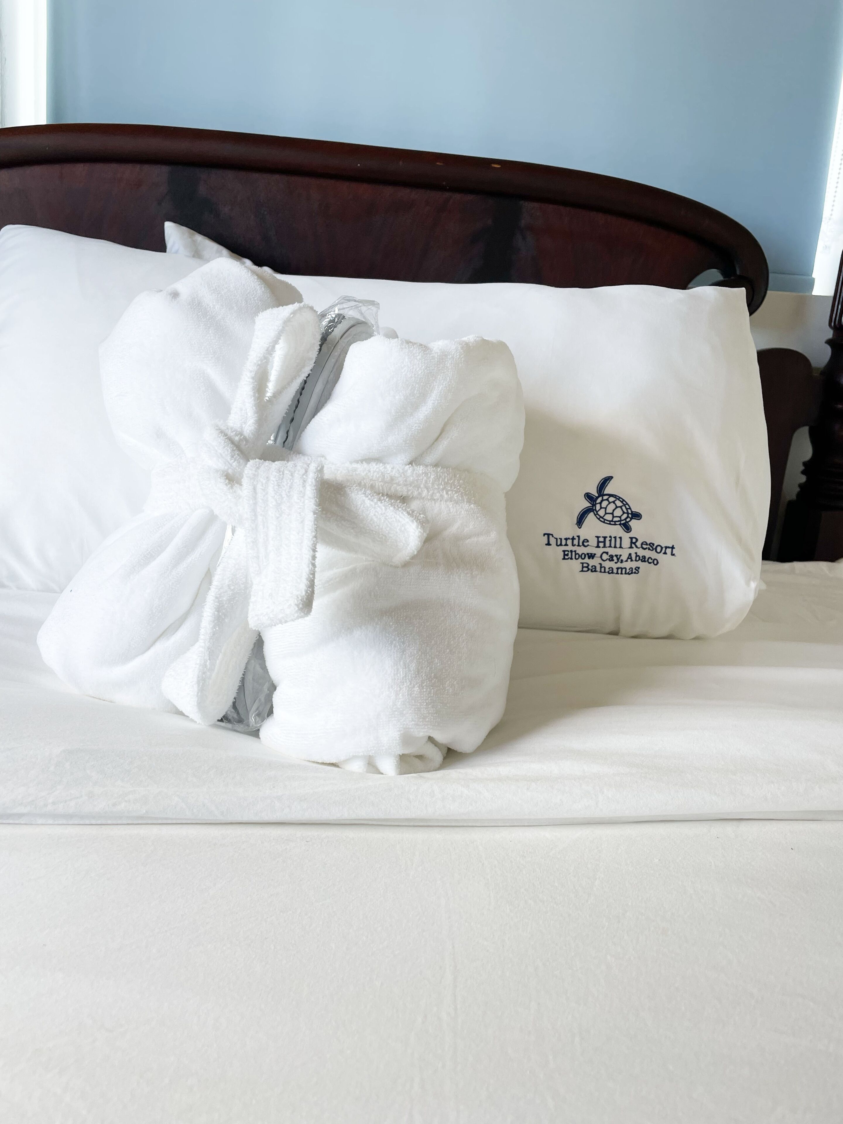 Un letto rifatto con cura, un asciugamano bianco e un cuscino con il logo del Turtle Hill Resort.