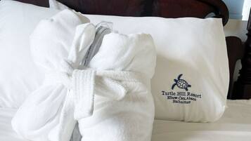 Un letto rifatto con cura, un asciugamano bianco e un cuscino con il logo del Turtle Hill Resort.