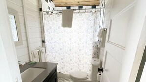 Een kleine badkamer met een houten plafond, een witte wastafel, een toilet en een douchegordijn met een sterrenpatroon.