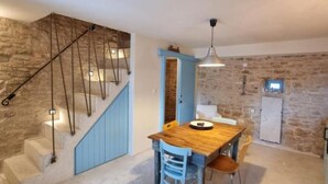 Ein Essbereich mit Holztisch und -stühlen, eine Treppe mit blauer Akzentwand und eine Steinwand im Hintergrund.