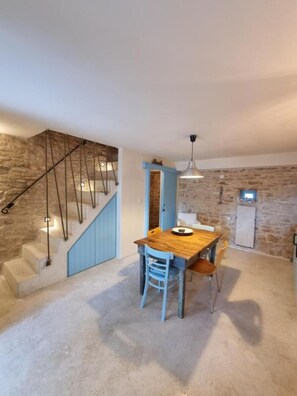 Ein Essbereich mit Holztisch und -stühlen, eine Treppe mit blauer Akzentwand und eine Steinwand im Hintergrund.