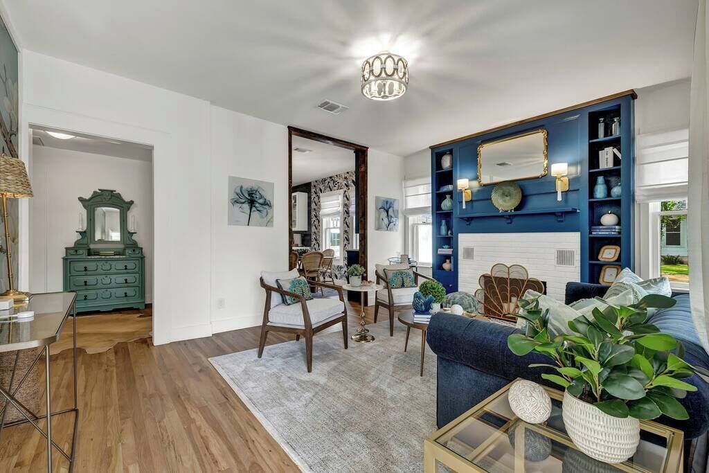 A living room with a sofa, chairs, a coffee table, a blue bookshelf, and a mirror.