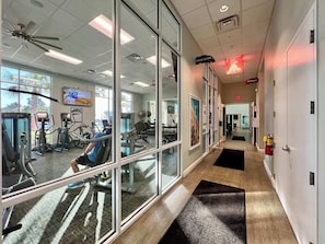 A fitness center with exercise equipment, a ceiling fan, and a sign for the fitness center.
