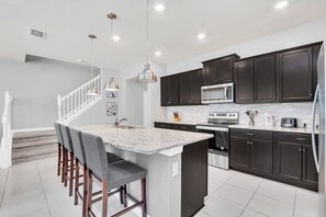 A modern kitchen with dark cabinets, a central island, and stainless steel appliances.