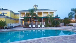 A swimming pool area with a building featuring a balcony and lounge chairs.