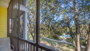 A balcony with a view of a landscaped area and a swimming pool.