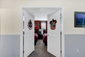 A hallway with two doors leading to a room with a bed and a desk. - Harry Potter | Superhero Gameroom | Waterpark 1308 (Davenport)