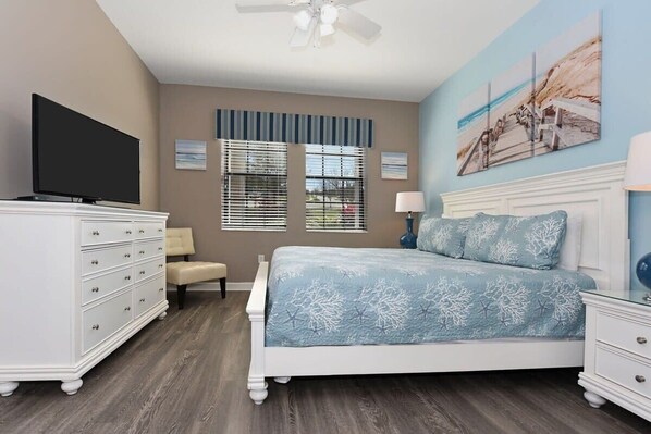 A bedroom with a bed, a dresser, a TV, and a window with blinds.