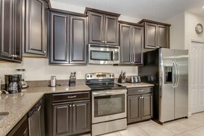 A modern kitchen with dark cabinets, stainless steel appliances, and a granite countertop.