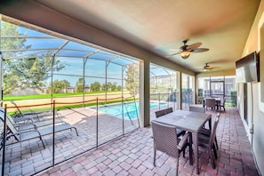 Un patio techado con piscina, mobiliario exterior y ventiladores de techo.