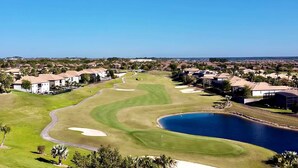 Un campo de golf con un estanque, rodeado de edificios residenciales.